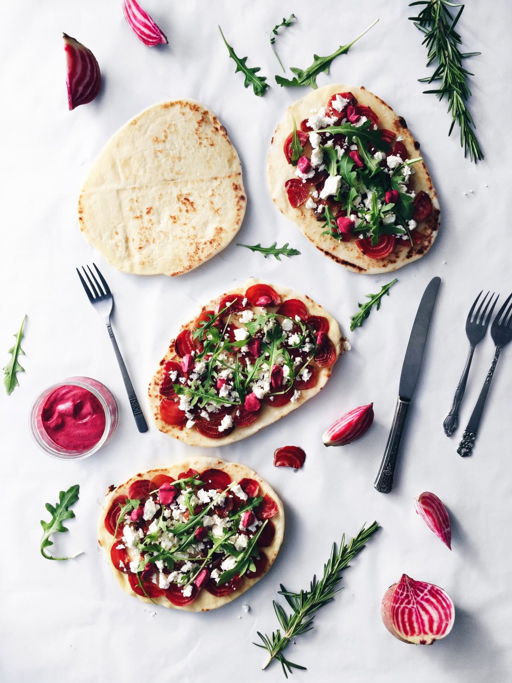 Pizza sur pains naan aux betteraves, au fromage de chèvre, au romarin et à la roquette