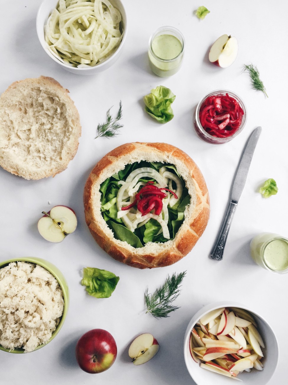 Grande miche de pain farcie aux pommes, fenouil, fromage de chèvre, aneth, oignons rouges marinés et laitue boston