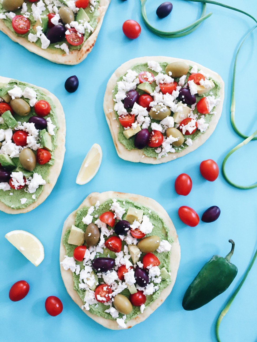 Pizza au pesto de coriandre et fleur d'ail, tournesol, tomates, olives, avocats, mozzarella et cumin