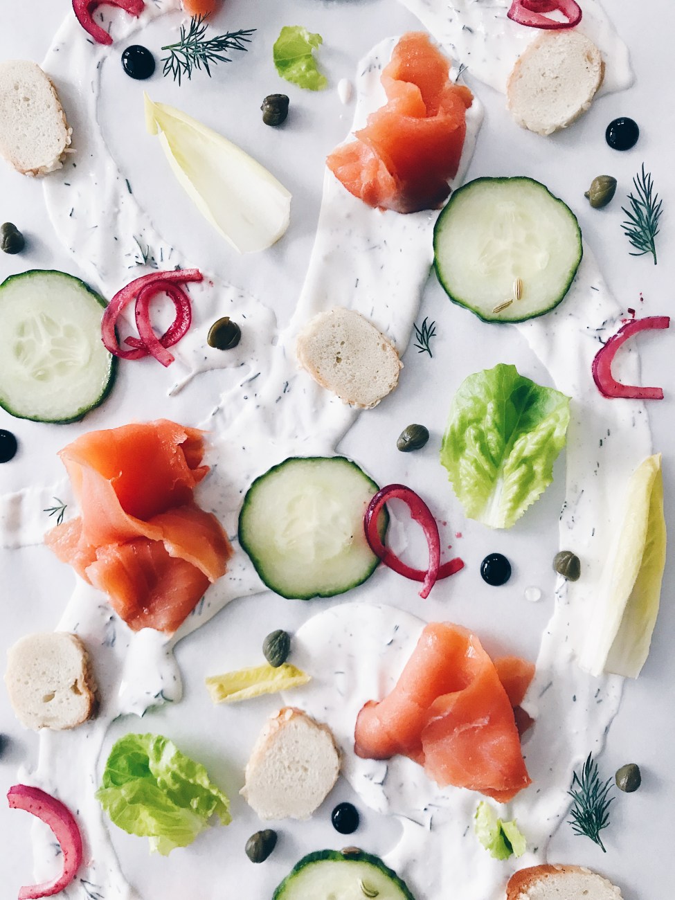 Entrée servie sur la table : saumon fumé, fromage à la crème, légumes marinés et bagel