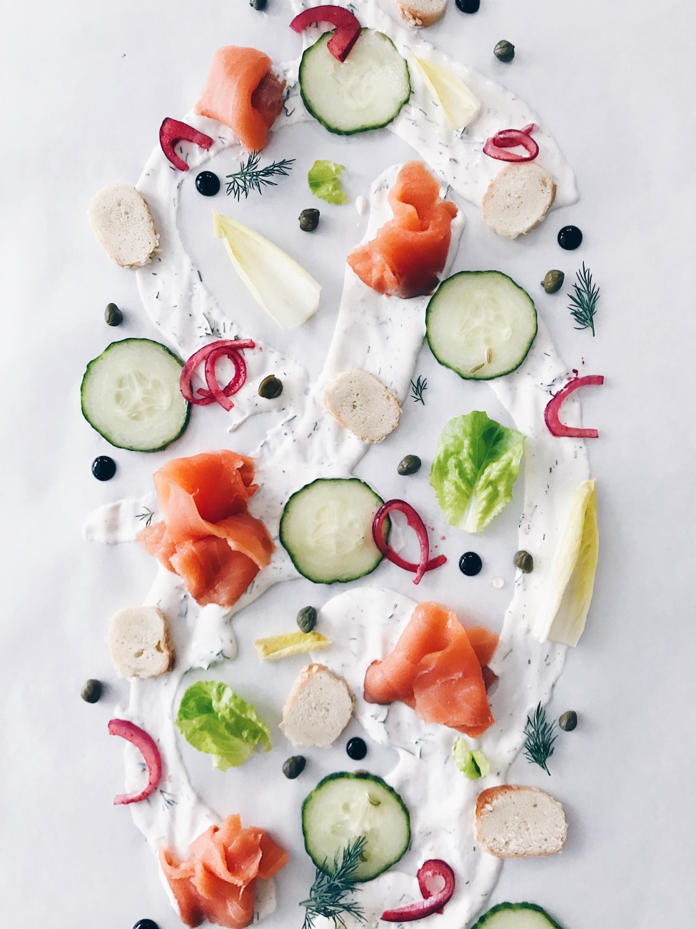 Entrée servie sur la table : saumon fumé, fromage à la crème, légumes marinés et bagel